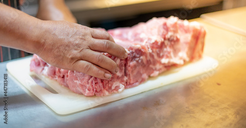 The male hand of Chef cutting raw beef on a chopping board prepares to cook in the kitchen at the restaurant.