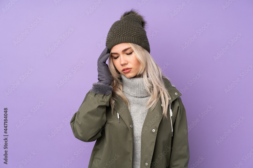 Teenager blonde girl with winter hat over isolated purple background with headache Teenager blonde girl with winter hat over isolated purple background with headache