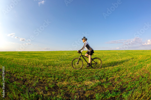 The cyclist rides a bicycle on the green grass on the field. Outdoor sports. Healthy lifestyle.