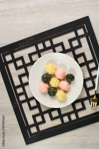 Three Color Kkultteok is Ball Shaped Rice Cake Filled with Honey and Sesame Syrup, Korean Traditional Cake for Chuseok Day. Served on White Plate photo
