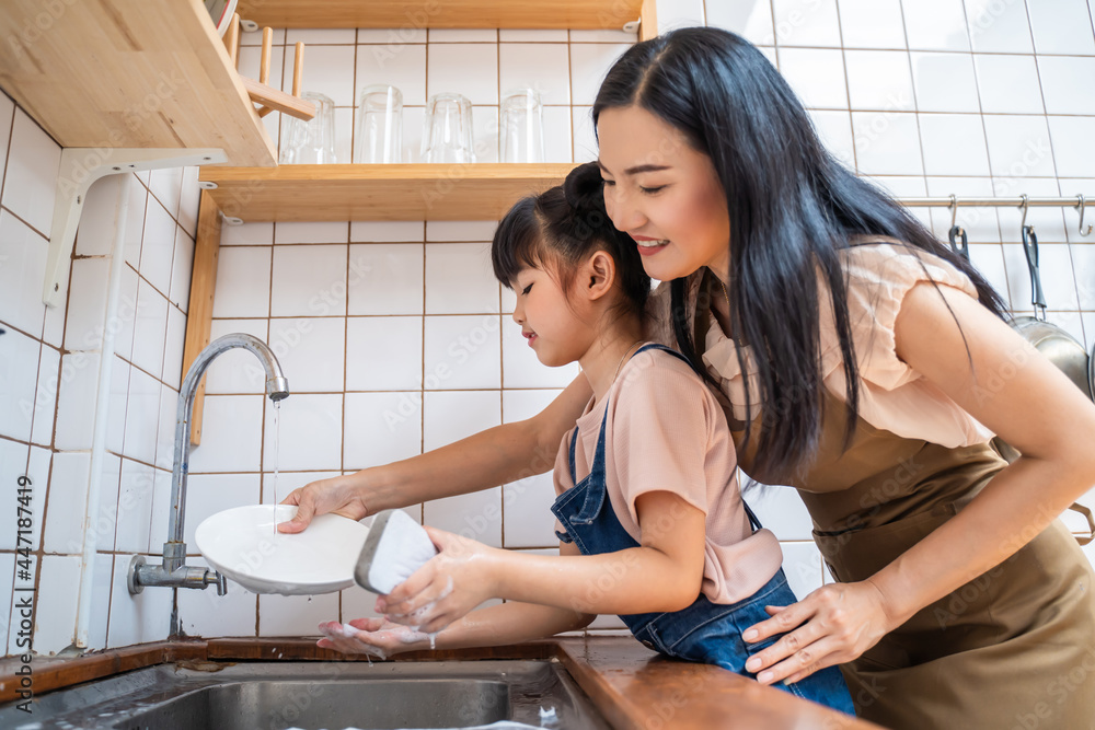 Asian loving mom teach young preschool girl to wash dishes in house. Asian loving mom teach young preschool girl to wash dishes in house.