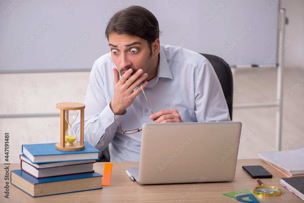 Young male teacher in time management concept Young male teacher in time management concept