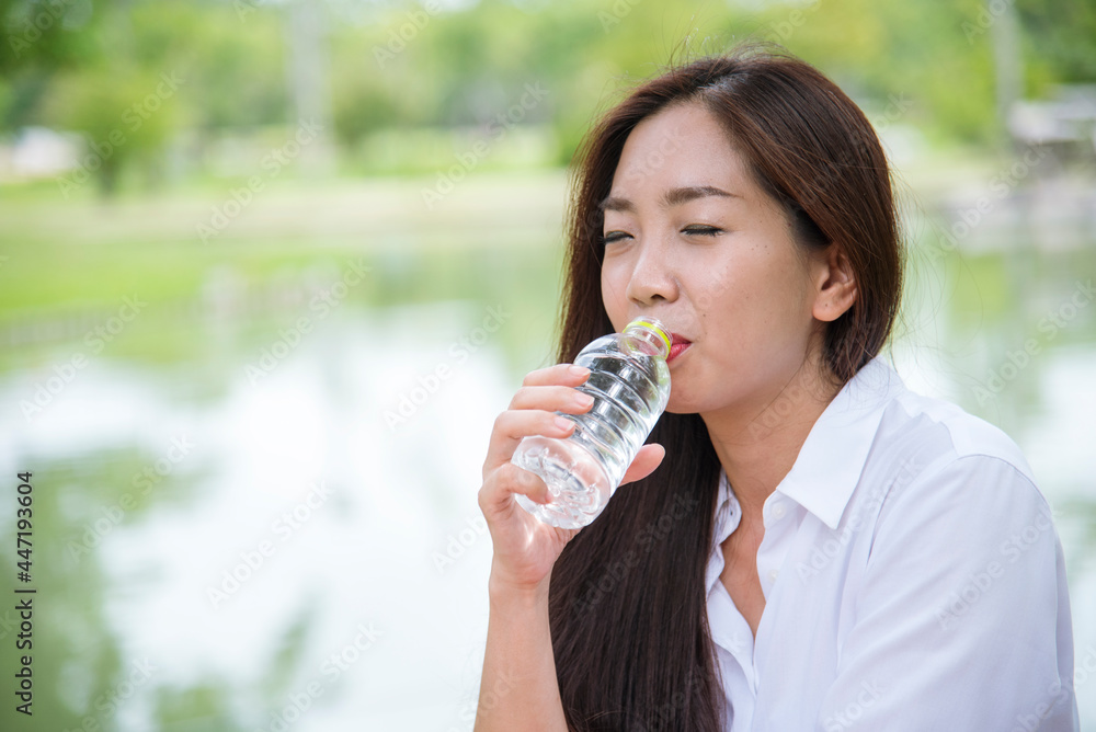Young Woman Drinking Water from bottle in green garden Park. Asian female drinking water bottle healthy person happy and smiling. Happiness Beautiful asian chinese women holding mineral water bottle Young Woman Drinking Water from bottle in green garden Park. Asian female drinking water bottle healthy person happy and smiling. Happiness Beautiful asian chinese women holding mineral water bottle
