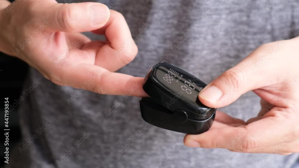A device to measure the oxygen saturation of a person at the fingertips. And checking oxygen depletion is an emergency sign of pneumonia caused by the COVID-19 virus. Video Slow motion A device to measure the oxygen saturation of a person at the fingertips. And checking oxygen depletion is an emergency sign of pneumonia caused by the COVID-19 virus. Video Slow motion