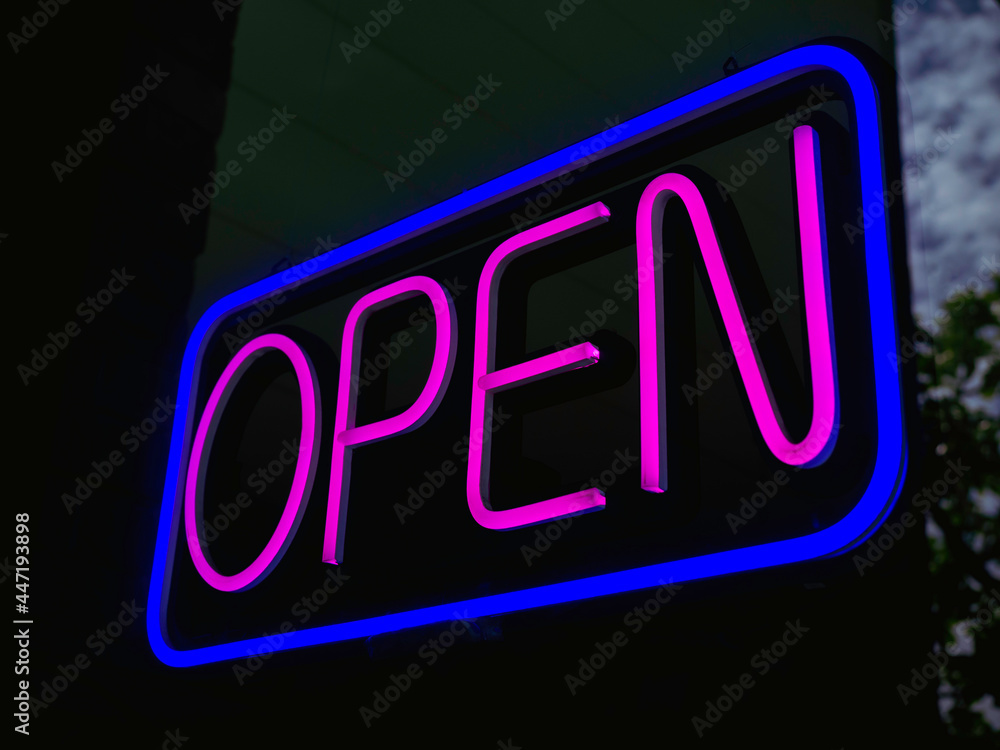 OPEN neon sign on glass at the entrance to bar or cafe, dark background, illuminated pink text in a blue square sign saying OPEN neon sign on glass at the entrance to bar or cafe, dark background, illuminated pink text in a blue square sign saying