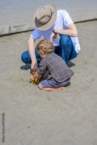 Φωτογραφία Uncle and little nephew are playing with toys in the sand on the children playgr