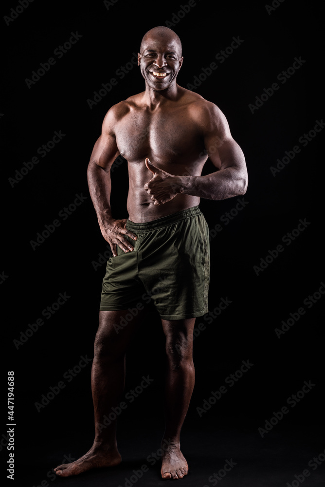 Fototapeta premium Cheerful adult muscular man standing looking at camera doing thumbs up