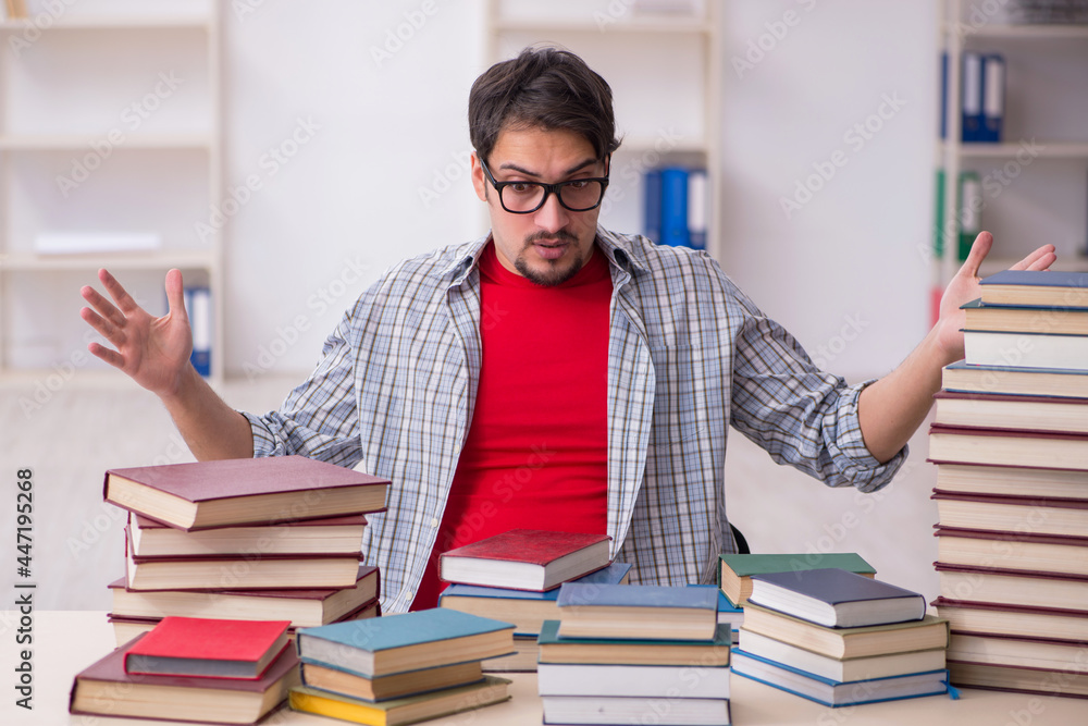 Young male student and too many books in the classroom Young male student and too many books in the classroom