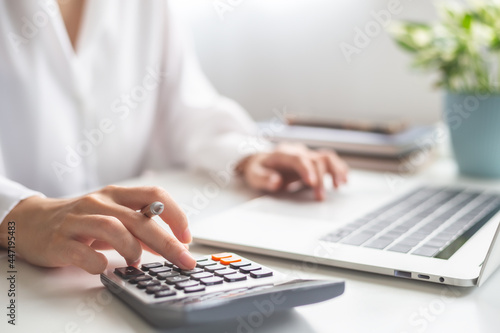 Fotografiet Woman entrepreneur using calculator, Saving money and calculating financial expense at home office concept