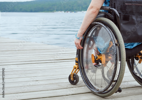 Woman in a wheelchair looking at the sea, part of the image, with copy space