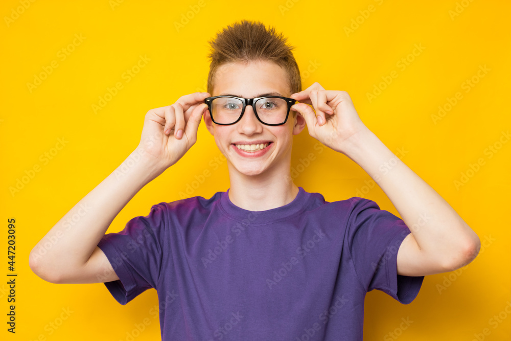 Back to school. Close up studio photo portrait of happy teen boy wearing glasses on yellow background Back to school. Close up studio photo portrait of happy teen boy wearing glasses on yellow background