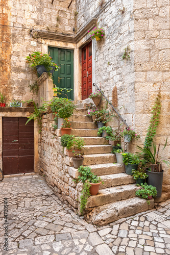 Fototapeta Naklejka Na Ścianę i Meble -  Picturesque street in Trogir city with flower pots and fresh laundry