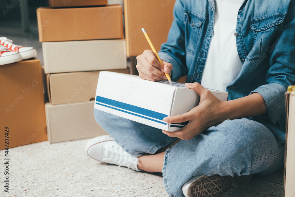 Obraz premium Online small business owner writing address on parcel box.