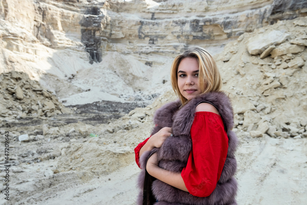 Gorgeous fashion model wear fur coat standing at dry empty sand quarry Gorgeous fashion model wear fur coat standing at dry empty sand quarry