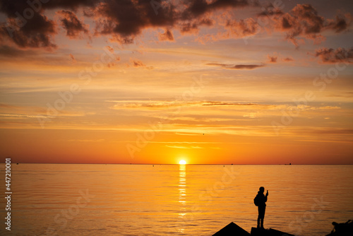 Woman or man standing on rock looking straight. Nature and beauty concept. Orange sundown. Girl silhuette at sunset.
