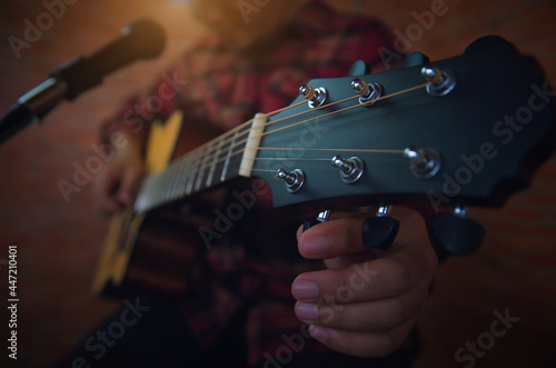 A musician is tuning the guitar into the speaker before playing the music.