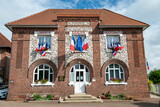 Facade d'une mairie avec drapeaux français bleu blanc rouge et européen, à l'occasion de la fête nationale du 14 juillet. Devise sur la facade : Liberté, Egalité, Fraternité
