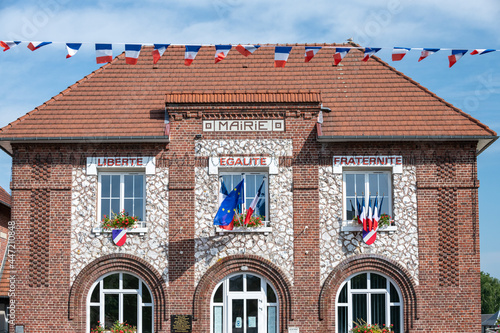 Facade d'une mairie avec drapeaux français bleu blanc rouge et européen, à l'occasion de la fête nationale du 14 juillet. Devise sur la facade : Liberté, Egalité, Fraternité