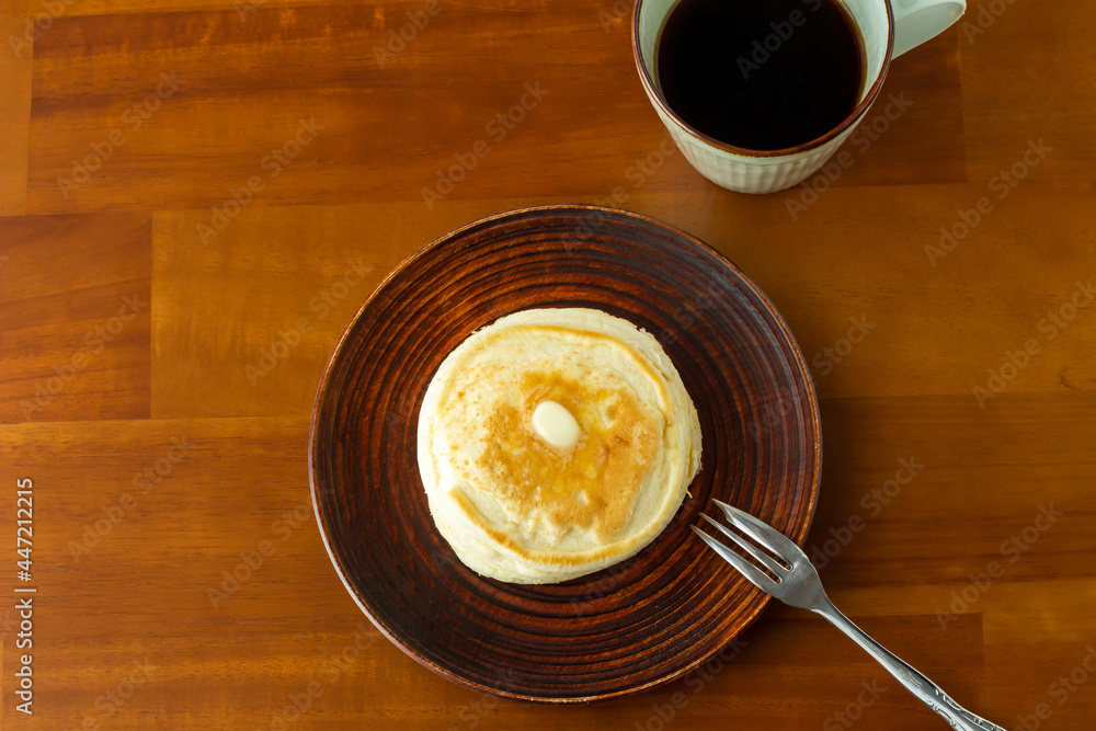 バターののったパンケーキとコーヒーの入ったカップ バターののったパンケーキとコーヒーの入ったカップ