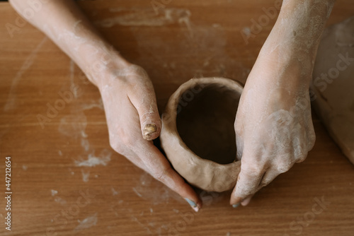 Top view of female hands sculpt utensils from clay.