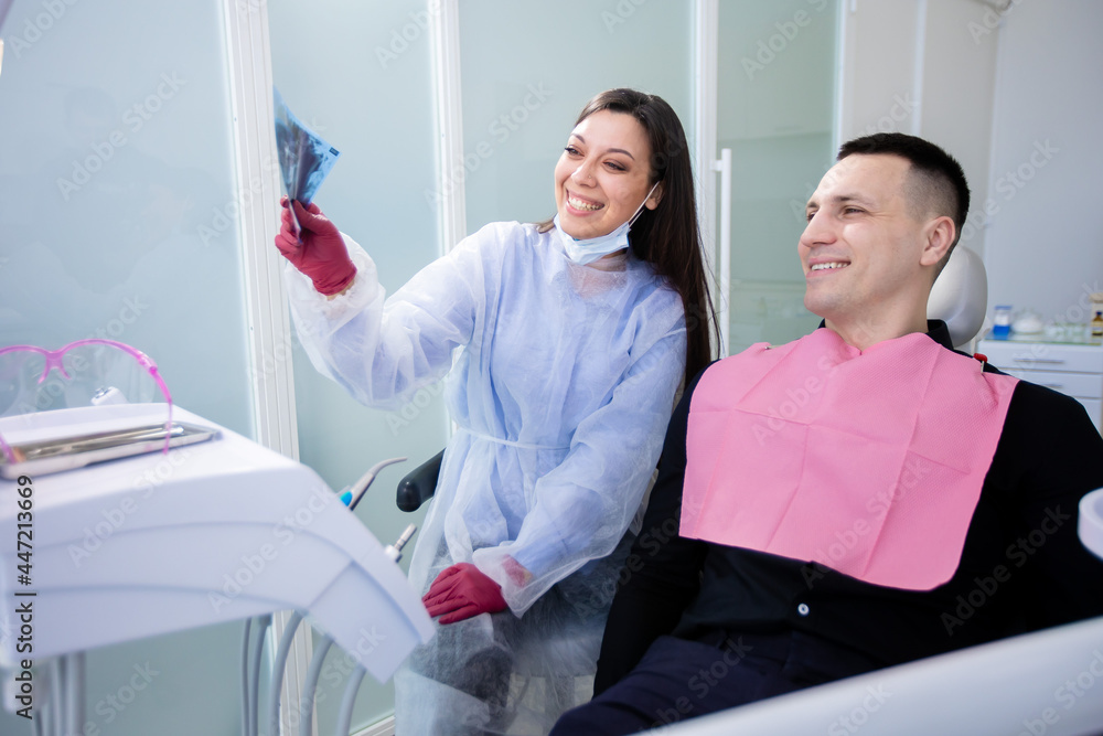 Happy female dentist and patient examining xray of healthy teeth