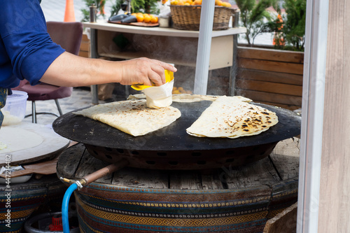 traditional turkish cuisine, street food: pancake. local woman cooks on metal sheet, in which she puts cheese, spinach, or potatoes. Selective Focus .
