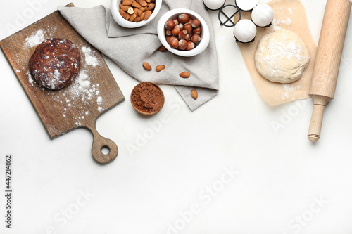 Fresh dough with ingredients for preparing bakery and utensils on light background