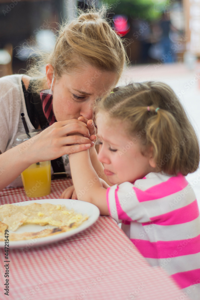 Her mother tries to comfort the little girl whose hand hurts while eating Hot Pancakes. Her mother tries to comfort the little girl whose hand hurts while eating Hot Pancakes.