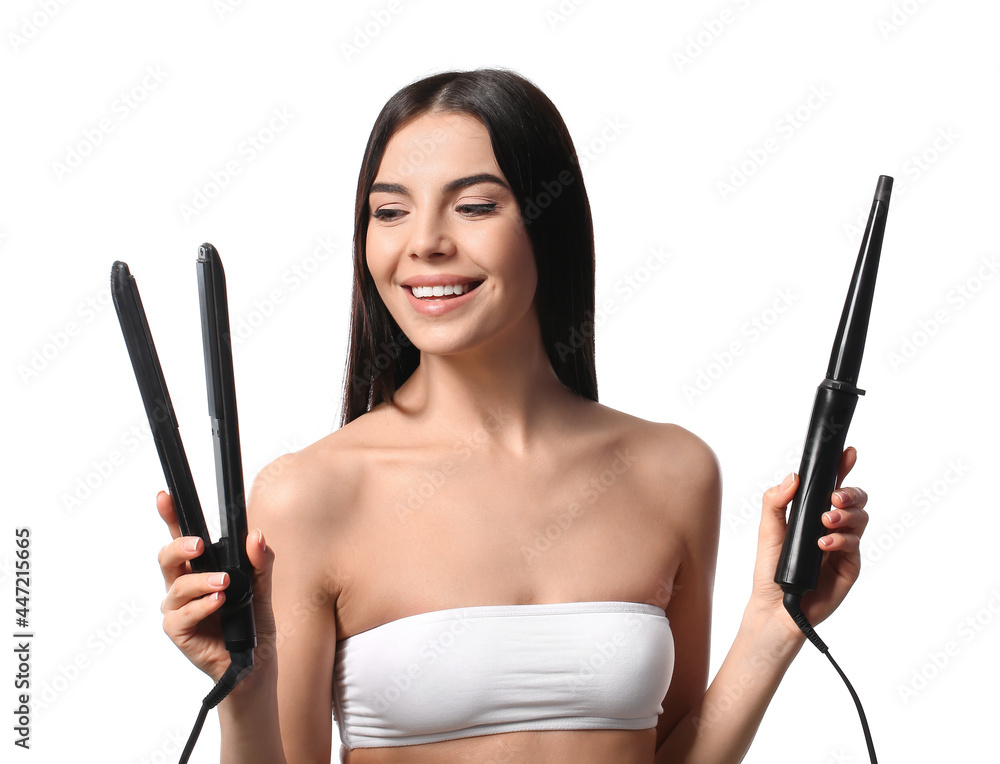Fototapeta premium Beautiful young woman with flattening and curling irons on white background