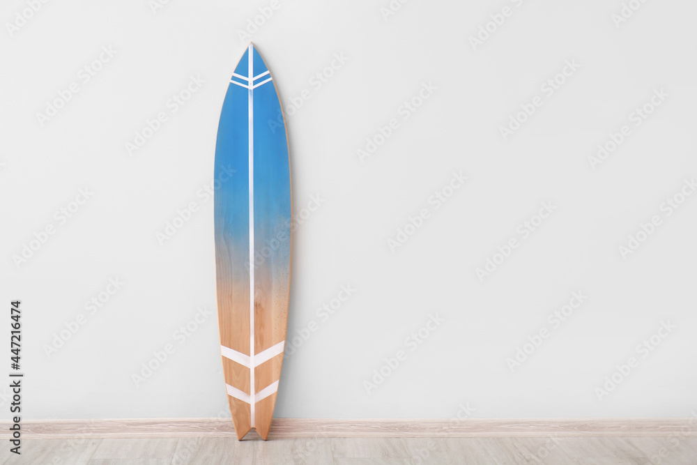 Blue surfboard near light wall - obrazy, fototapety, plakaty 