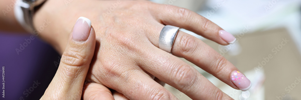 Woman tries on wide silver ring on her finger Woman tries on wide silver ring on her finger