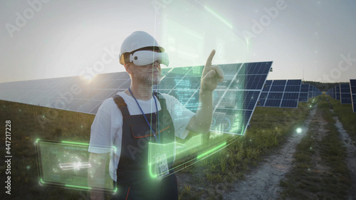 Adult male worker using VR glasses checking solar battery panels tapping online. 3D graphic system. Sunset sky. Futuristic technology innovation. Eco business trend. Virtual reality inspiration. 5G
