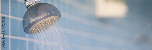 Water flows from rain shower in trickles into hotel bathroom photo