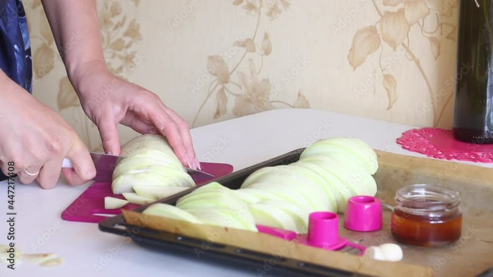 The woman is cutting the vegetable marrow. Vegetables, oil and garlic for cooking lie side by side The woman is cutting the vegetable marrow. Vegetables, oil and garlic for cooking lie side by side