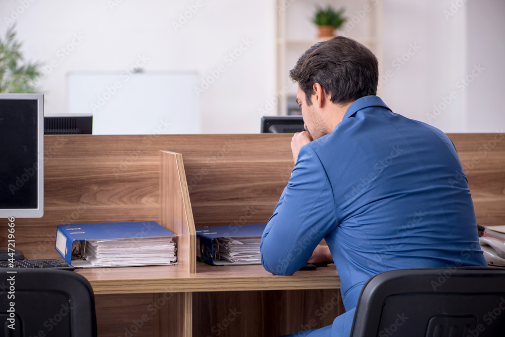 Young male employee sitting at workplace Young male employee sitting at workplace