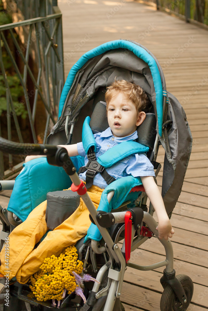 Disability a disabled child in a wheelchair is resting on the street. The concept of a happy life Disability a disabled child in a wheelchair is resting on the street. The concept of a happy life