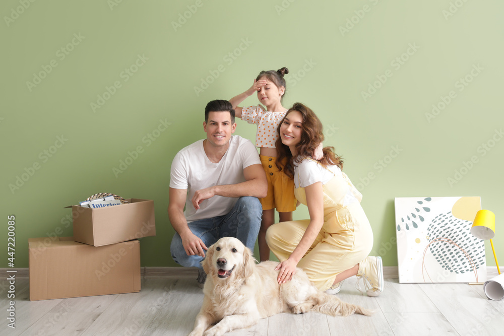Fototapeta premium Happy family with dog and belongings near color wall