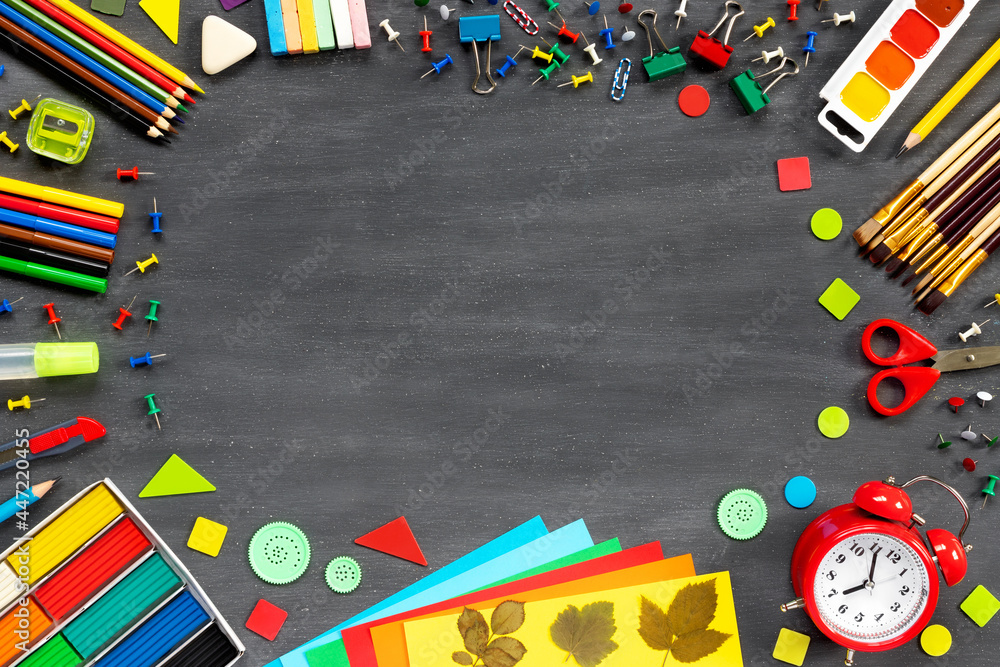 Paints, brushes, felt-tip pens, pencils on school board. Scissors, paper and other school supplies. Red alarm clock top view. Paints, brushes, felt-tip pens, pencils on school board. Scissors, paper and other school supplies. Red alarm clock top view.