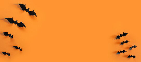 Halloween card with black bats on orange background. Banner for congratulations or invitation.
