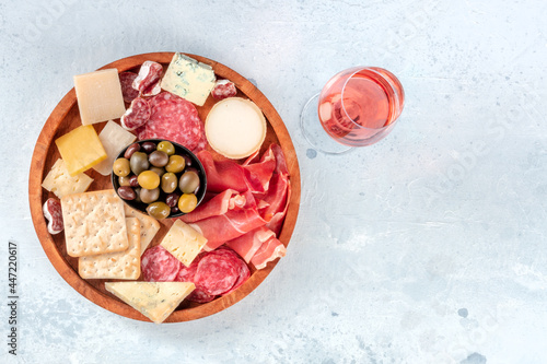 Charcuterie and cheese platter, overhead shot with rose wine. Prosciutto di Parma ham, salami, blue cheese, olives and crackers, gourmet appetizers with a place for text