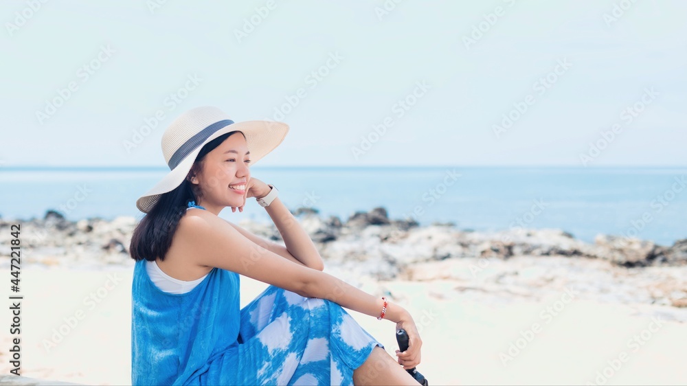 Asian traveler woman sitting and relaxing at the beach by the sea background.Concept of happy travel on vacation weekend.