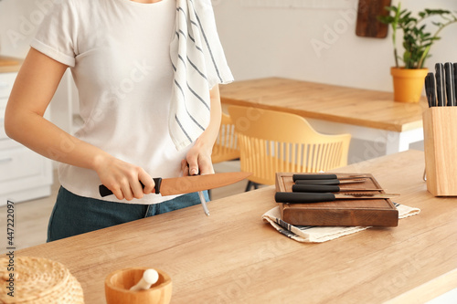 Woman sharpening knife in kitchen photo