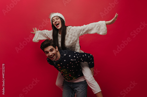 Fotografie Charming young man in Christmas jersey smiling and posing with stylish girlfrien