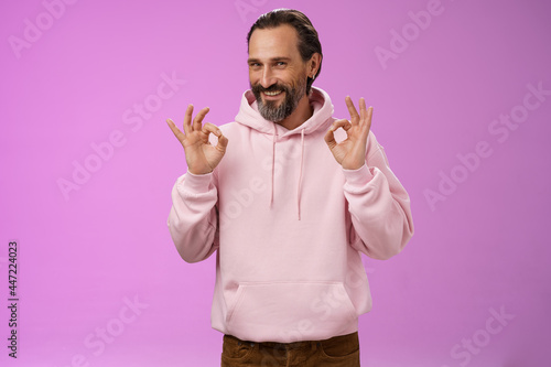 Devious tricky good-looking happy mature man 50s bearded grey hair show okay excellent perfection gesture smug smirking mysterious have everything under control, assuring all fine, purple background