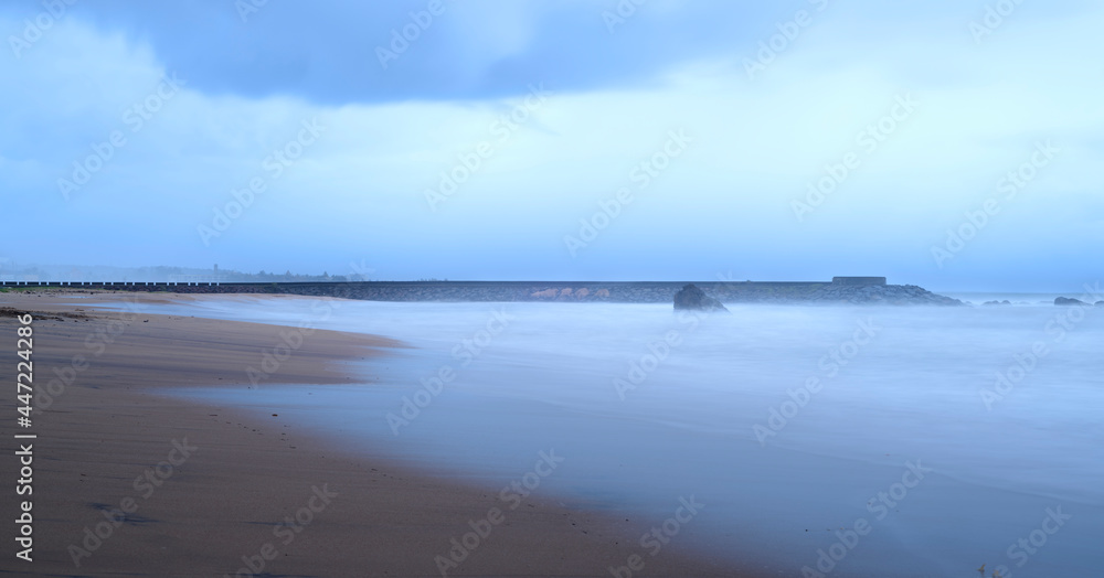 Empty sandy beach in the paradise island of Sri Lanka, evening long exposure photograph. concept of the covid situation in the beautiful beaches, silky smooth sea waves washing the sand.