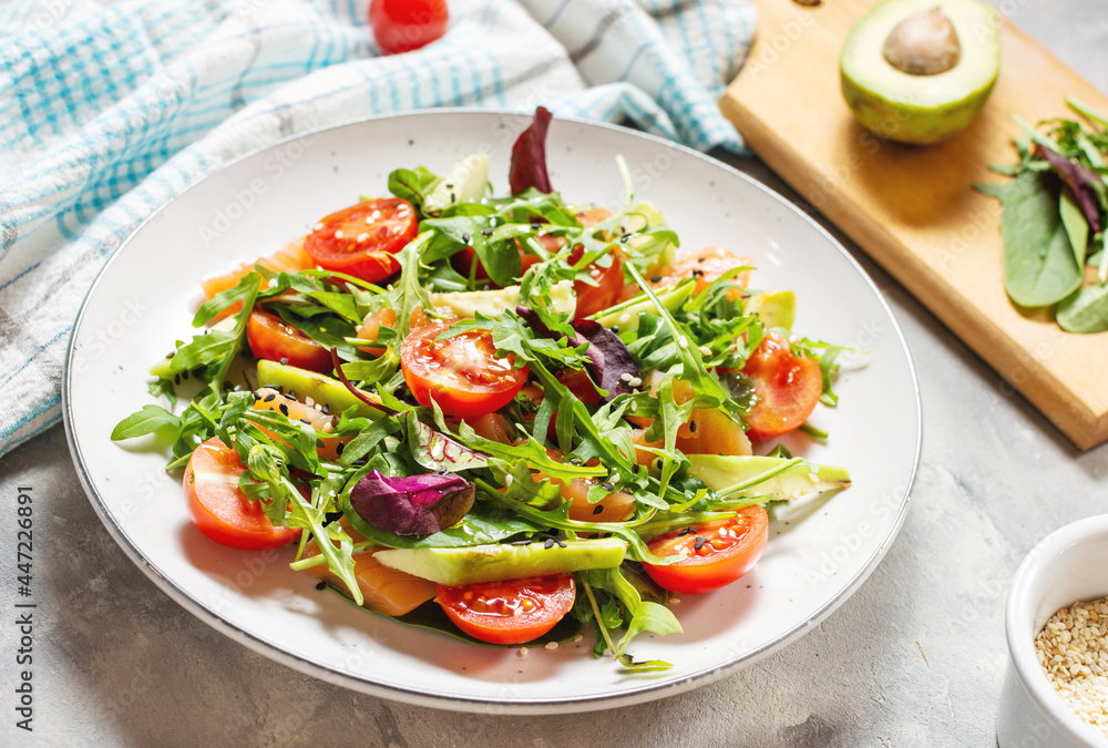 Salmon salad with green leaves, avocado and cherry tomato on concrete background Salmon salad with green leaves, avocado and cherry tomato on concrete background