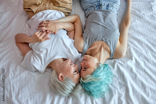 Lesbian couple in the morning, happy wake-up, hugging and kissing, top view portrait on pretty ladies in domestic clothes spending weekends at home, relaxed and happy. copy space. people lifestyle