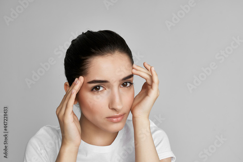 woman in white t-shirt holding face dissatisfaction problem isolated background