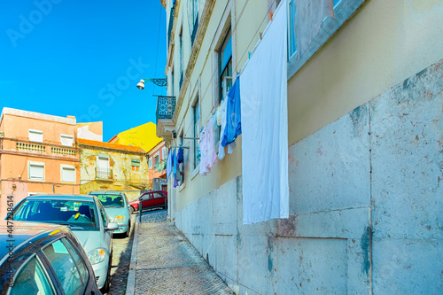 Travel Concepts and Ideas. Colorful Drying Linen Along of Line of Cars in One of Streets of Portugal at daytime.