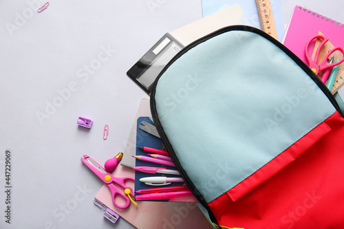 School backpack and stationery on light background